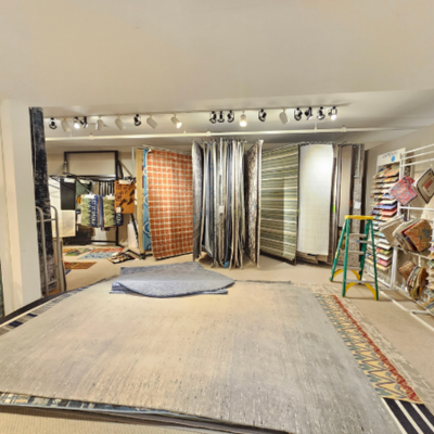 Area rug section at Barlett's Home Interiors showroom in Charlevoix, MI, featuring colorful rugs on racks and floor displays.